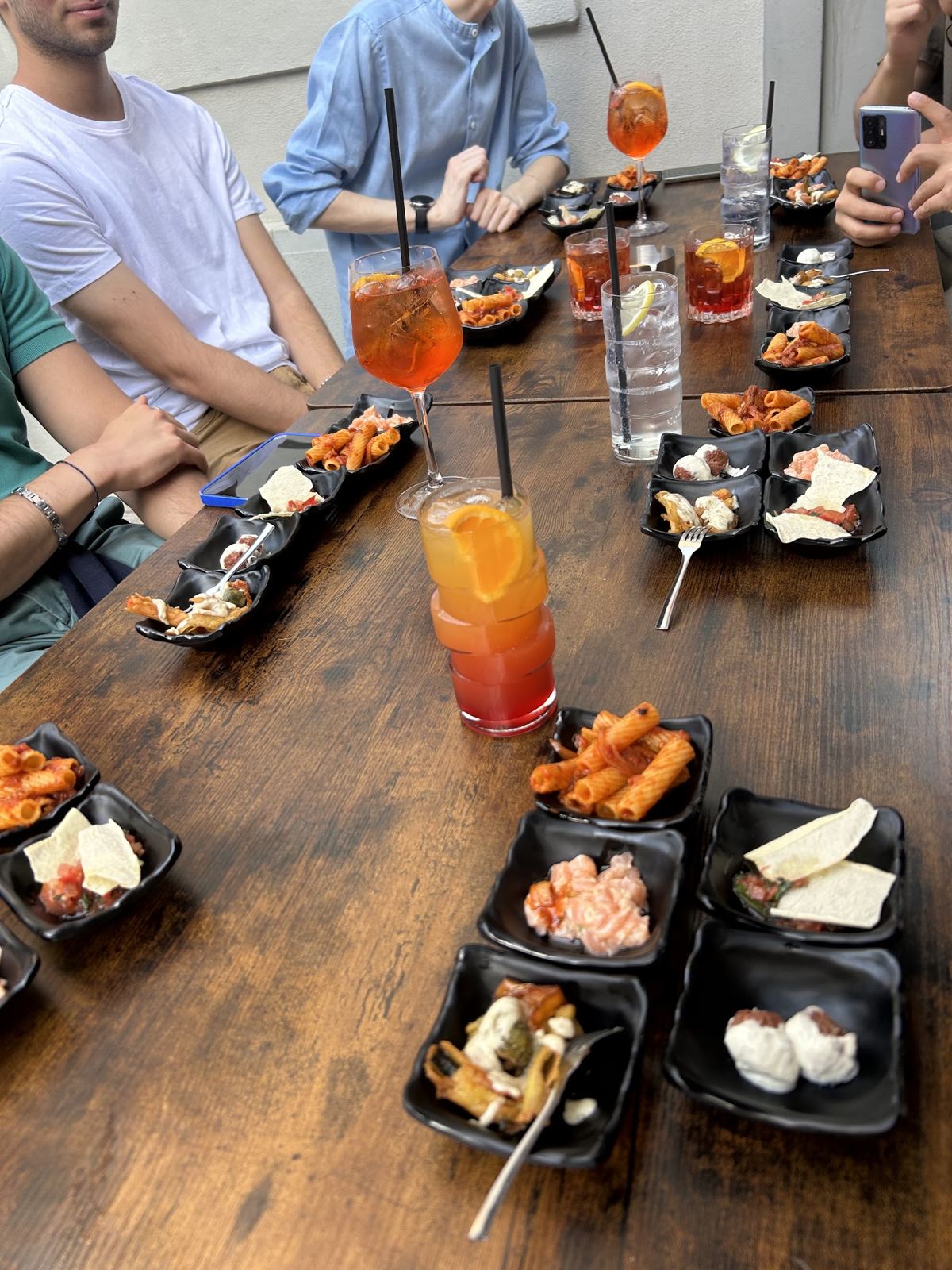 Tavolo pieno di vassoi di tapas e cocktail all'aperto