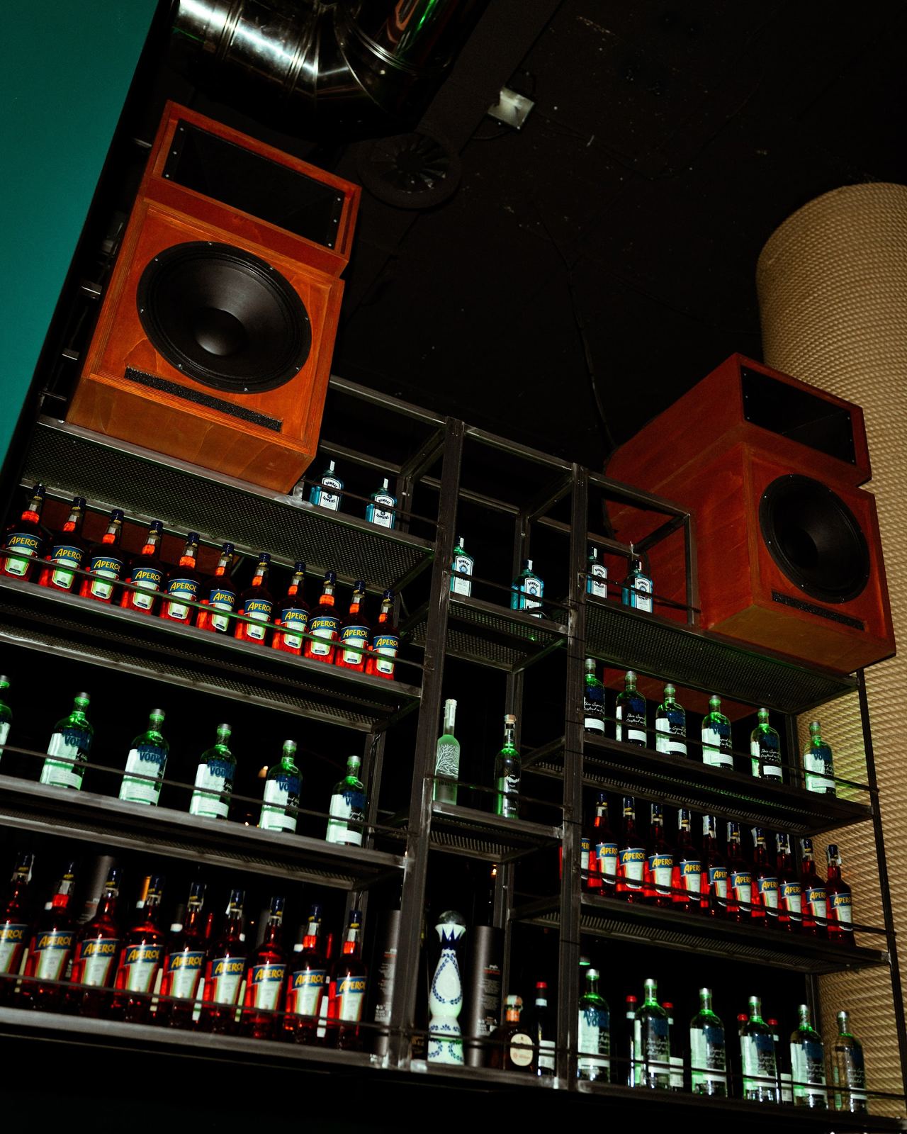 Il retrobanco del bar con le bottiglie illuminate e le casse arancioni