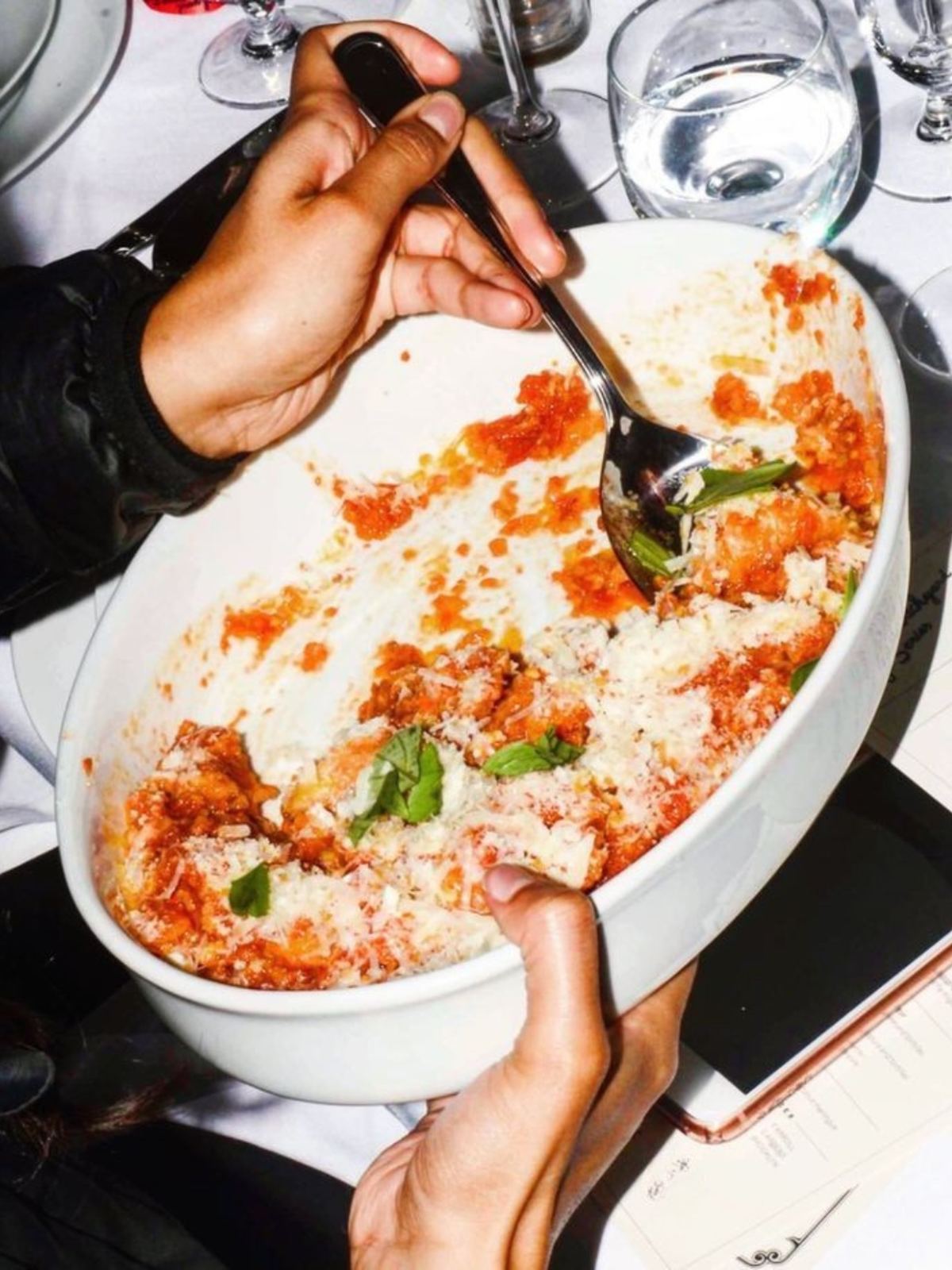 Una teglia di pasta al forno con pomodoro e basilico, servita a tavola